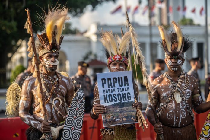 Masyarakat adat Papua dari suku Awyu yang mengenakan cat tubuh tradisional dan penutup kepala burung cendrawasih berkumpul bersama para aktivis untuk mengadakan protes di depan Istana Presiden di Jakarta (walhipapua.org).